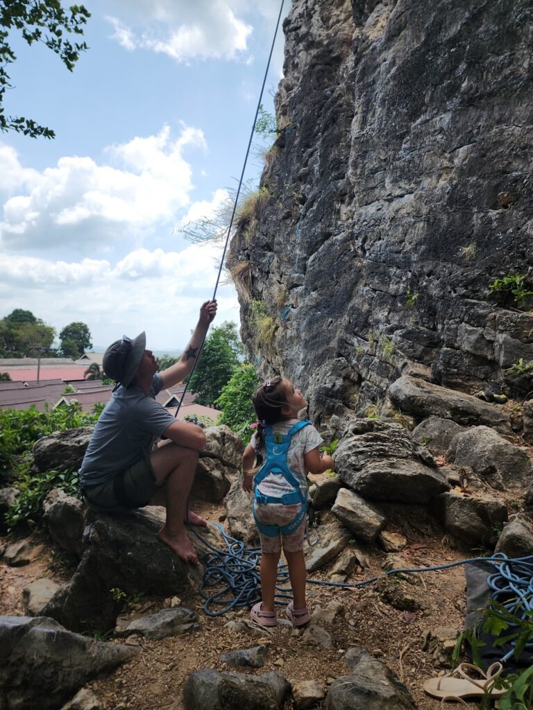 Girl rock climbing with her dad in Thailand
